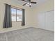 Cozy bedroom with neutral carpet, ceiling fan, and large window with stylish gray curtains at 4665 E Dartmouth St, Mesa, AZ 85205