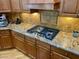 Gourmet kitchen with stainless steel cooktop, tile backsplash, granite countertops and custom cabinetry at 4665 E Dartmouth St, Mesa, AZ 85205