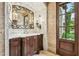 Elegant bathroom featuring a marble sink, ornate mirror, stone-tiled walls, and a door with outdoor view at 5902 E Arcadia Ln, Phoenix, AZ 85018