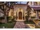 Arched entrance featuring a wooden door, sconce lighting, lush landscaping, and a decorative fountain at 5902 E Arcadia Ln, Phoenix, AZ 85018