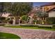 View of the front yard with brick driveway, lush lawn, mature trees, and an arched gate entrance to the property at 5902 E Arcadia Ln, Phoenix, AZ 85018
