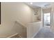 A carpeted hallway with railing, decorative artwork, and a glimpse of a bedroom at 7726 E Baseline Rd # 156, Mesa, AZ 85209