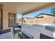 Covered patio area with outdoor seating overlooking the sparkling pool and spa in a private backyard at 7908 W Harmony Ln, Peoria, AZ 85382
