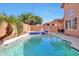Sparkling swimming pool with baja step, spa, and lounge chairs next to lush palm trees and patio at 7908 W Harmony Ln, Peoria, AZ 85382