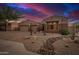 Desert home featuring a three-car garage, gravel landscaping with native plants, and decorative rocks at 9604 S 183Rd Dr, Goodyear, AZ 85338