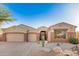 Single-story home featuring a three car garage and desert landscaping with rock and native plants at 9604 S 183Rd Dr, Goodyear, AZ 85338