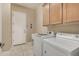 Well-lit laundry room with front-loading washer and dryer, utility sink, and ample cabinet storage at 9604 S 183Rd Dr, Goodyear, AZ 85338