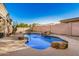 Private pool featuring rock details and waterfall in a desert landscaped backyard with beige concrete and block fencing at 9604 S 183Rd Dr, Goodyear, AZ 85338
