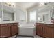 Bright bathroom featuring dual sinks, a large tub, wood cabinets, and natural light at 10162 E Theorem Dr, Mesa, AZ 85212