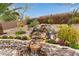 Scenic backyard featuring a tiered rock waterfall and vibrant desert flora, perfect for relaxation at 10796 E Betony Dr, Scottsdale, AZ 85255
