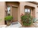 View of a front door with potted plant and blooming shrubbery offering a warm welcome at 10796 E Betony Dr, Scottsdale, AZ 85255
