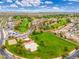 Beautiful aerial view of a community with a golf course, grassy area, and homes with a blue sky above at 14906 W Luna N Dr, Litchfield Park, AZ 85340