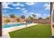 Backyard featuring a pool, putting green and lounge chairs surrounded by lush landscaping and mature trees at 14906 W Luna N Dr, Litchfield Park, AZ 85340