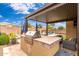 Outdoor kitchen and barbecue area under the covered patio, overlooking the pool and putting green at 14906 W Luna N Dr, Litchfield Park, AZ 85340