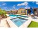Backyard pool and spa combination with lounge chairs, palm trees, turf and blue umbrellas at 14906 W Luna N Dr, Litchfield Park, AZ 85340
