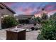 Stunning backyard retreat featuring a custom water fountain, stone path, and lush landscaping under a vibrant sunset sky at 1528 E Harrison St, Gilbert, AZ 85295