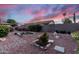 Charming backyard featuring decorative rock, patio, and lush desert landscaping under a vibrant sunset sky at 1528 E Harrison St, Gilbert, AZ 85295
