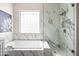 Bathroom with marble shower, soaking tub, granite vanity, and bright window at 1528 E Harrison St, Gilbert, AZ 85295