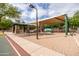 Community playground with covered seating, swings, and climbing structure on a well-maintained sand lot at 1528 E Harrison St, Gilbert, AZ 85295