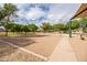 Sand volleyball court with net surrounded by lush greenery and sidewalks under a partly cloudy sky at 1528 E Harrison St, Gilbert, AZ 85295
