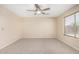 Bright bedroom featuring a ceiling fan, neutral carpeting, and a large window with natural light at 16508 N 114Th Dr, Surprise, AZ 85378