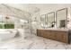 Bathroom featuring marble floors and walls, dual sinks, a soaking tub, a glass enclosed shower, and a view to the outside at 20690 E Sunset Dr, Queen Creek, AZ 85142