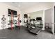 Spacious exercise room with workout equipment, mirrored wall, rubber flooring, and natural light at 20690 E Sunset Dr, Queen Creek, AZ 85142