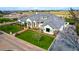 An aerial view shows the grand white brick home with a manicured lawn, brick driveway, and mature landscaping at 20690 E Sunset Dr, Queen Creek, AZ 85142