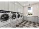 Spacious laundry room with four front load washer/dryers, farmhouse sink, and custom cabinetry for storage at 20690 E Sunset Dr, Queen Creek, AZ 85142