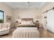 Bright bedroom with a wooden headboard, neutral toned walls, light colored floors, and ensuite bath at 20690 E Sunset Dr, Queen Creek, AZ 85142