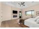 Light bedroom with a modern fireplace, tv, neutral toned walls, and a view of the pool through the window at 20690 E Sunset Dr, Queen Creek, AZ 85142