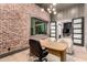 Modern office with a brick accent wall, light hardwood floors, and views of the backyard at 20690 E Sunset Dr, Queen Creek, AZ 85142