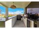 Outdoor kitchen with a built-in barbecue, pizza oven, and bar area at 20690 E Sunset Dr, Queen Creek, AZ 85142