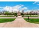 Community entrance featuring a stone tower, manicured trees, and lush landscaping under a blue sky at 20690 E Sunset Dr, Queen Creek, AZ 85142