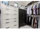 Spacious walk-in closet with custom white drawers, organized hanging clothes, and secure safe at 20690 E Sunset Dr, Queen Creek, AZ 85142