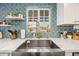 Farmhouse sink in the kitchen with a mosaic tile backsplash and floating wood shelves at 3126 N 17Th Dr, Phoenix, AZ 85015