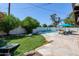 Backyard pool area with artificial turf, stone pavers, lounge chairs, mature trees, and well-maintained landscaping at 3514 N 83Rd St, Scottsdale, AZ 85251