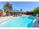 Sparkling pool with lounge chairs in a backyard with a brick house and mature landscaping under a clear blue sky at 3514 N 83Rd St, Scottsdale, AZ 85251