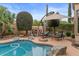 Cozy outdoor seating area by the pool with a fireplace and umbrella for shaded comfort at 4515 E Rakestraw Ln, Gilbert, AZ 85298