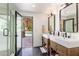Bright bathroom with double sinks, rustic wood vanities, black hardware, and an open shower leading to the pool area at 5040 N Arcadia Dr, Phoenix, AZ 85018