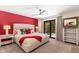 Cozy main bedroom with a plush upholstered bed, red accent wall, and serene backyard view at 5040 N Arcadia Dr, Phoenix, AZ 85018