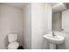 White bathroom with a pedestal sink, a toilet, and a large mirror at 5233 W Albeniz Pl, Phoenix, AZ 85043
