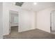 This carpeted bedroom features neutral walls and a view into an adjacent room at 5233 W Albeniz Pl, Phoenix, AZ 85043