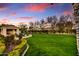 Expansive backyard with lush green lawn, mature trees, and covered patio with an inviting seating area at 5670 W Linda Ln, Chandler, AZ 85226