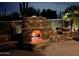 Inviting outdoor fireplace featuring a stone design and a glowing fire, perfect for cozy evenings in a desert landscape at 6181 E Brilliant Sky Dr, Scottsdale, AZ 85266