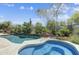 Inviting backyard featuring a sparkling pool, relaxing hot tub, lush landscaping, and stone accents, perfect for outdoor enjoyment at 6181 E Brilliant Sky Dr, Scottsdale, AZ 85266