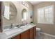 Bright bathroom featuring dual sinks with a marble counter top and a white shuttered window at 8861 E Sutton Dr, Scottsdale, AZ 85260