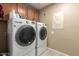 Well-lit laundry room featuring front-loading washer and dryer and upper wood cabinets at 8861 E Sutton Dr, Scottsdale, AZ 85260