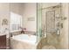 Beautiful main bathroom features a soaking tub, glass enclosed shower, and a window with plantation shutters at 8861 E Sutton Dr, Scottsdale, AZ 85260