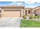 Charming beige home featuring a two-car garage, lush landscaping, and a welcoming arched entryway at 9608 E Nacoma Dr, Sun Lakes, AZ 85248